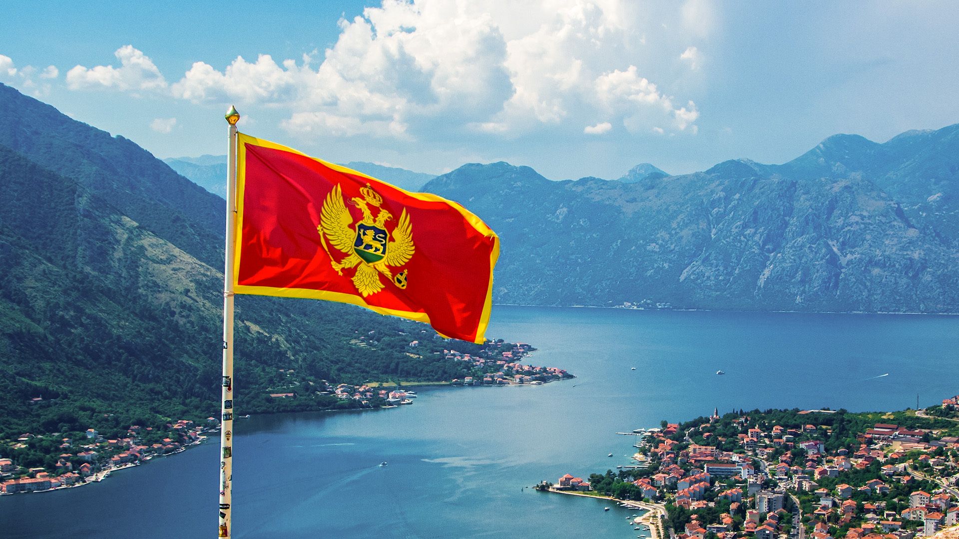 Montenegro flag waving in front of riverside and mountain landscape